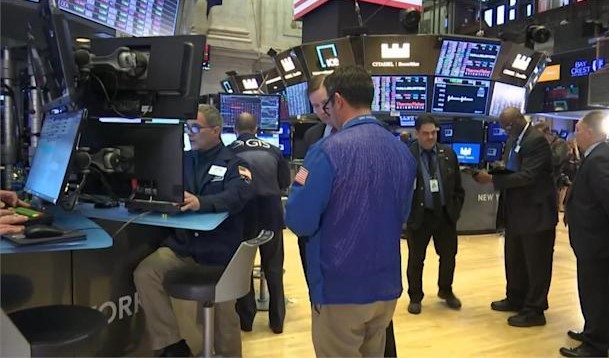 Two traders in US exchange is talking and the other traders are looking at the stock market trend
